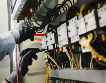 Electrical engineers test electrical installations and wiring on protective relays, measuring them with a multimeter.